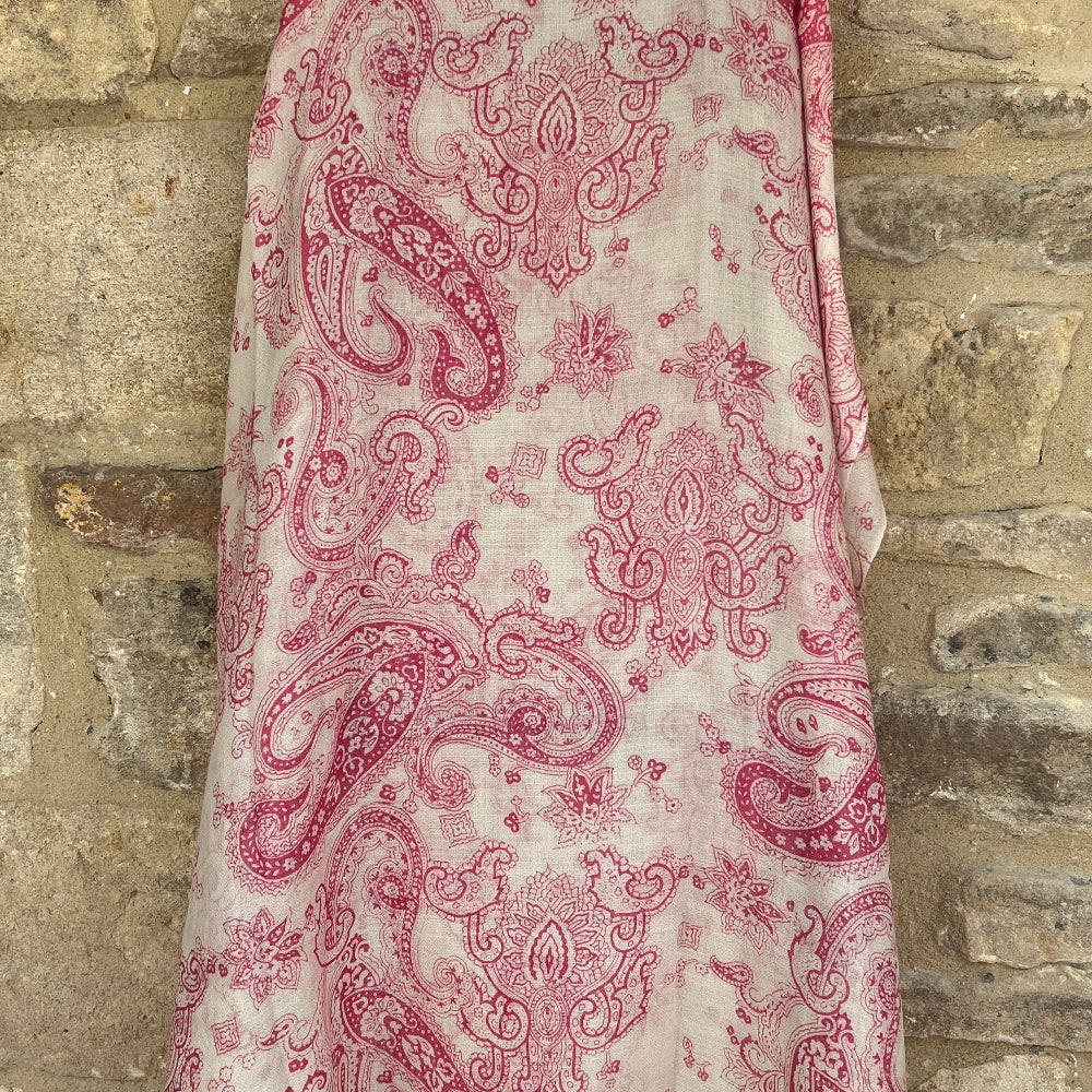 A pink paisley patterned cashmere pashmina draped over a stone wall