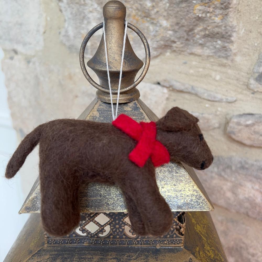 Crafted from premium wool, this handmade felted dog with warm chocolate tones are beautifully offset by a crimson scarf, meticulously hand-stitched to capture authentic detail.

A fun and lovely artisan created piece for those seeking distinctive, individually made décor or a meaningful gift with genuine character and quality. Show with festive holly on a gold fabric with a stone wall background. 
