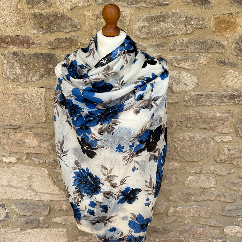 Cashmere Floral pashmina scarf with blue  flowers on a mannequin against a stone wall background