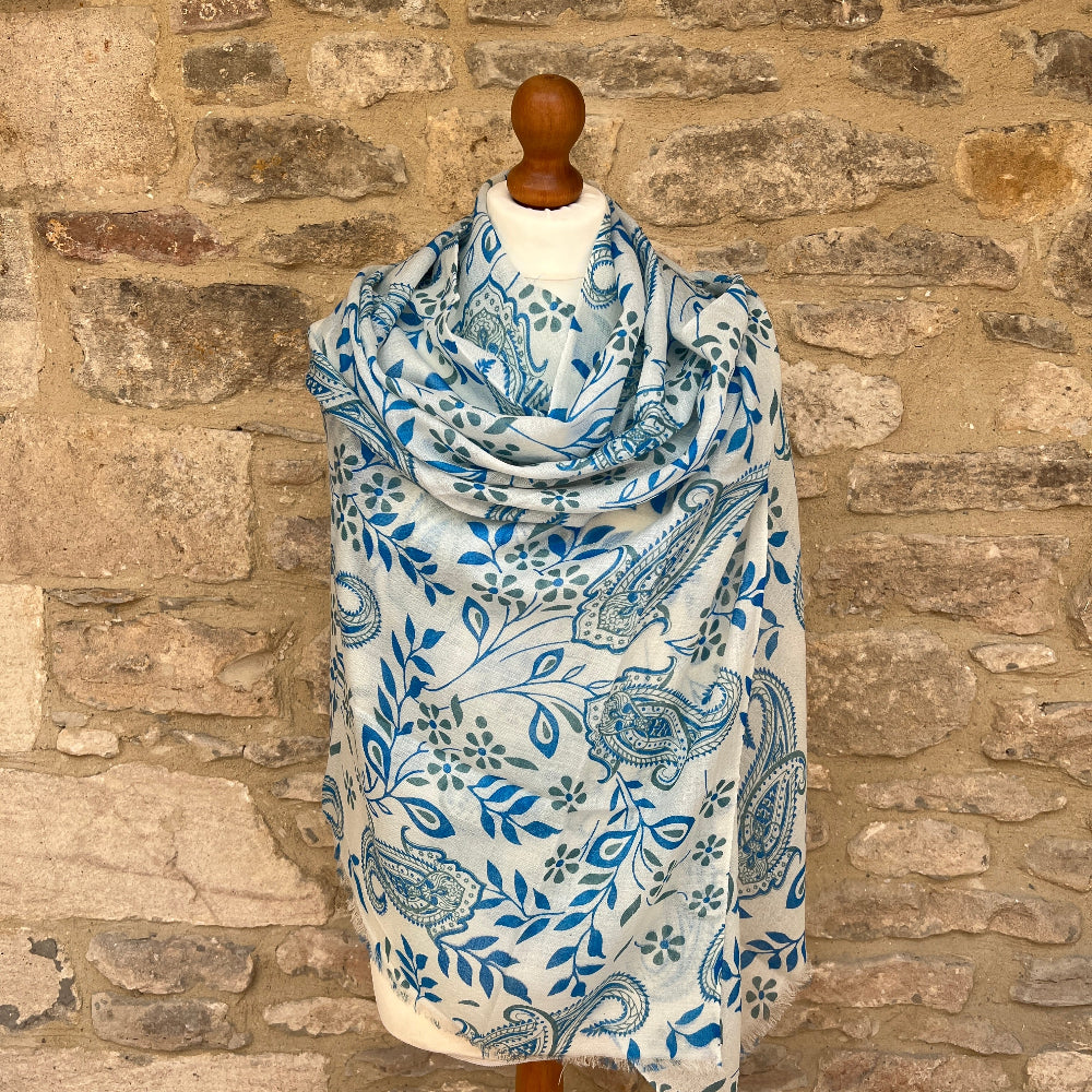 Blue and white patterned scarf on a mannequin against a stone wall background