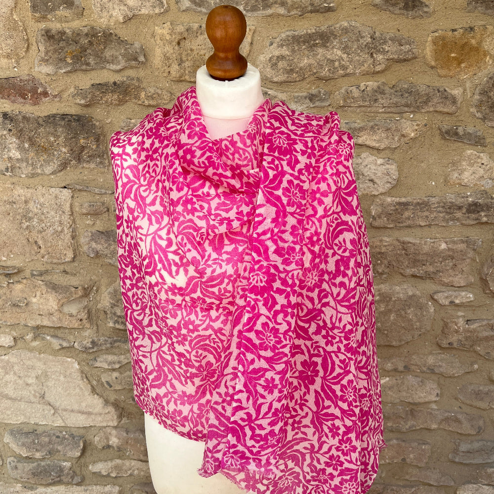 Mannequin wearing a pink floral scarf against a stone wall background