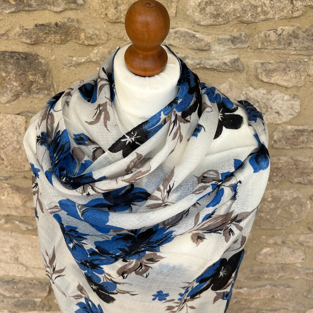 Cashmere Floral pashmina scarf with blue  flowers on a mannequin against a stone wall background