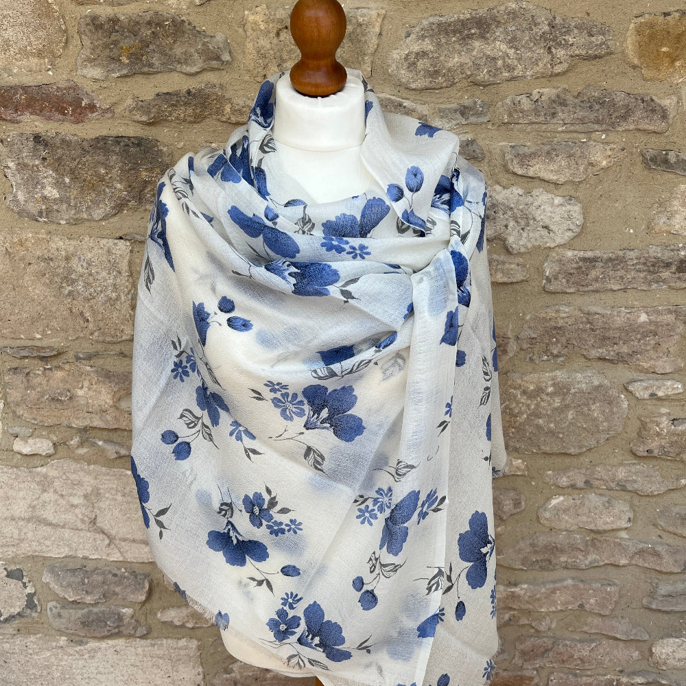 A gossamer cashmere scarf on a mannequin against a stone wall background. 