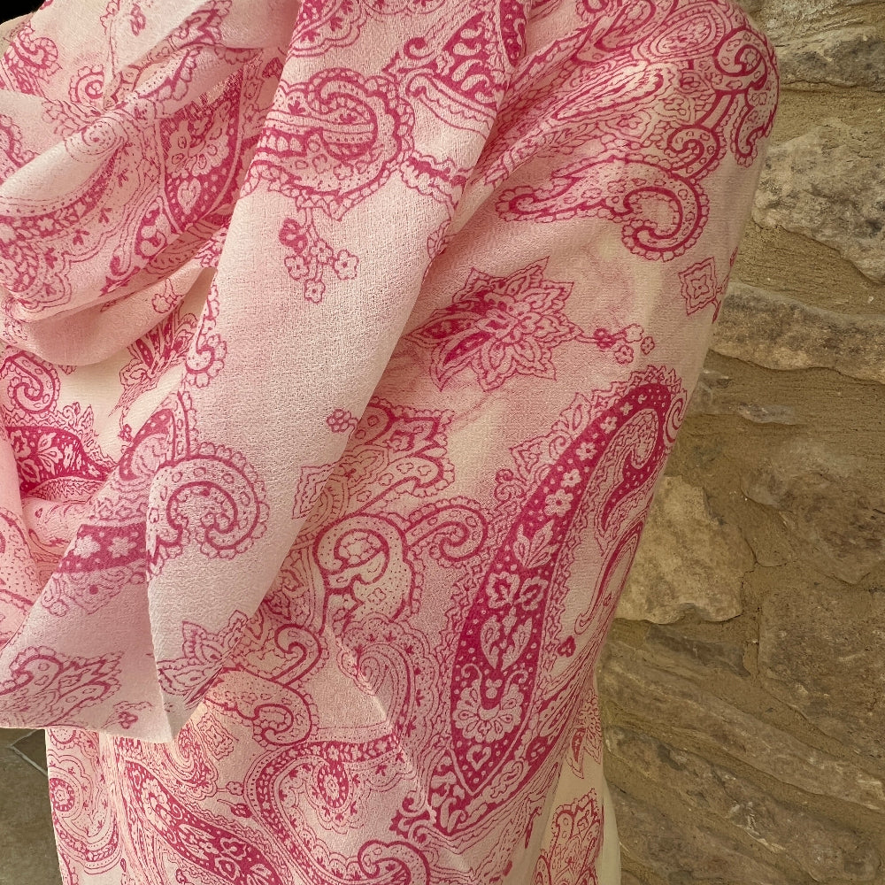 Pink paisley patterned cashmere pashmina against a stone wall background