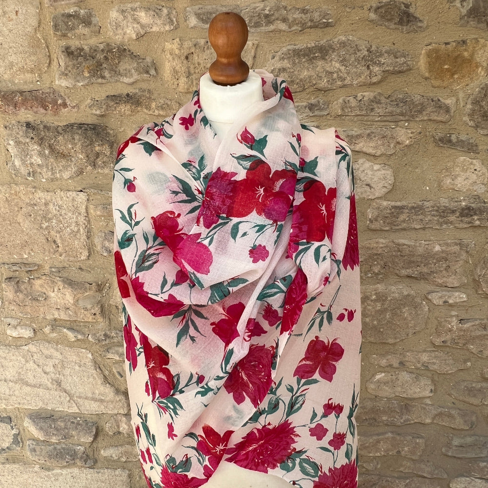Floral cashmere pashmina scarf draped over a wooden rod against a stone wall background