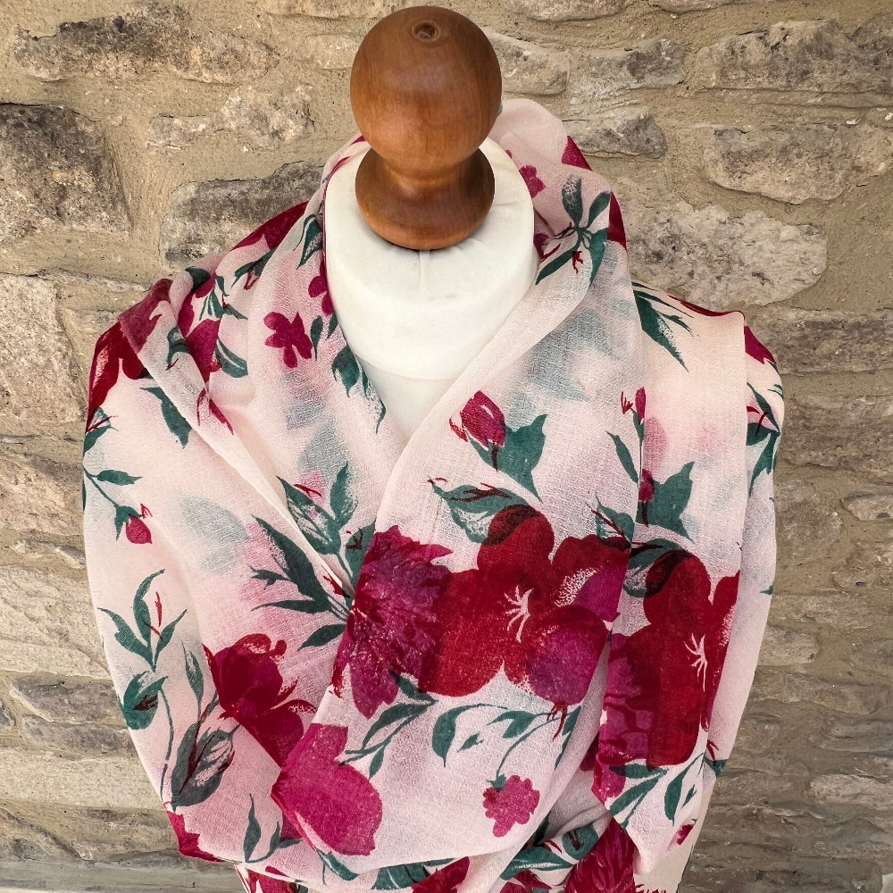 Floral cashmere pashmina scarf draped over a wooden rod against a stone wall background