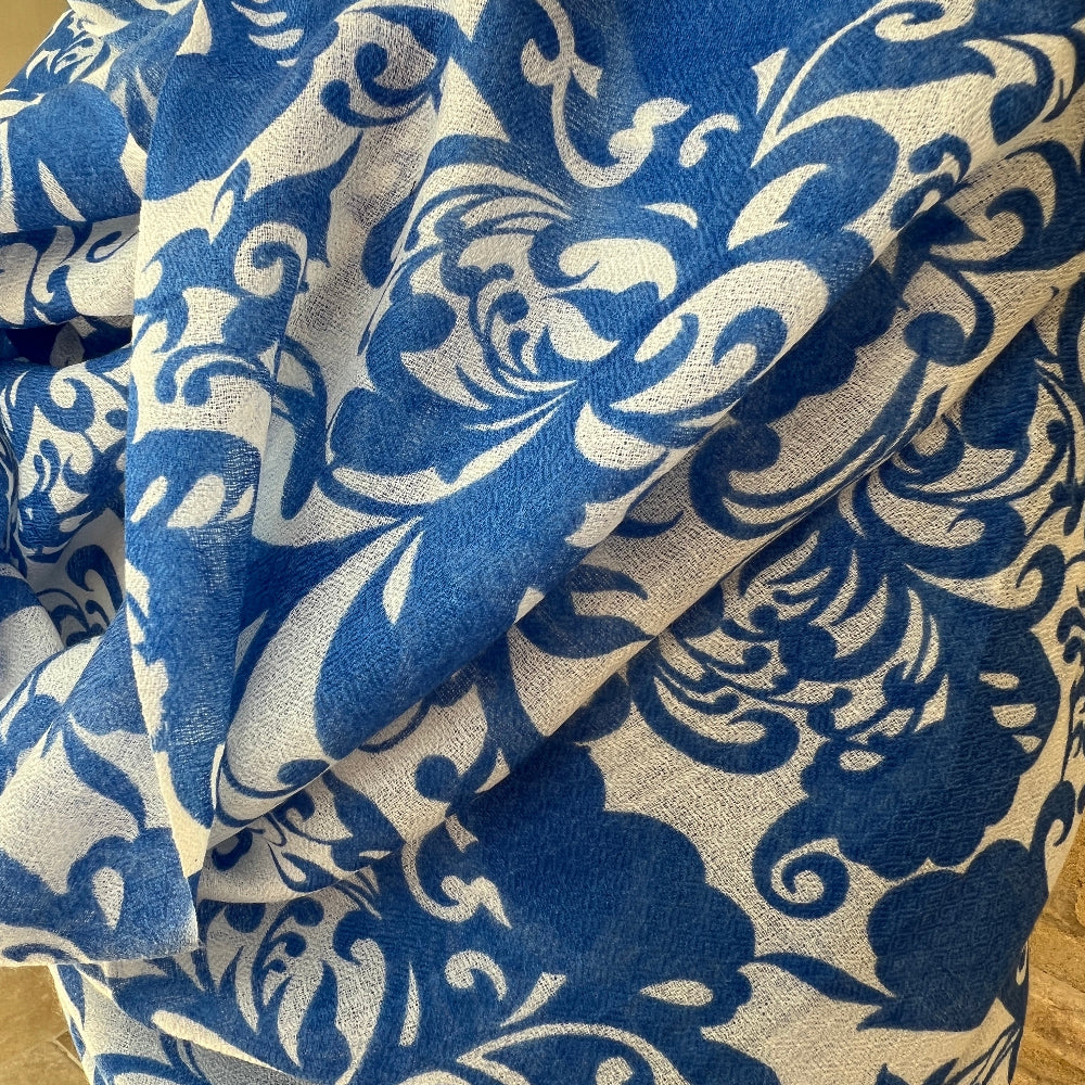 Close up of a Blue and white  patterned cashmere pashmina against a stone background.