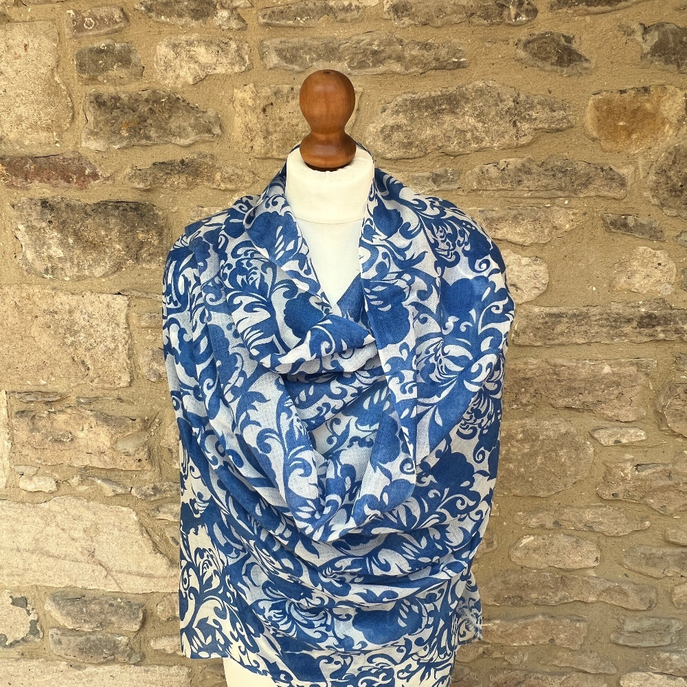 Blue and white patterned cashmere scarf / pashmina on a mannequin against a stone wall background