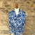 Blue and white patterned cashmere scarf / pashmina on a mannequin against a stone wall background