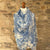 Mannequin wearing a blue and white paisley patterned cashmere pashmina scarf against a stone wall.