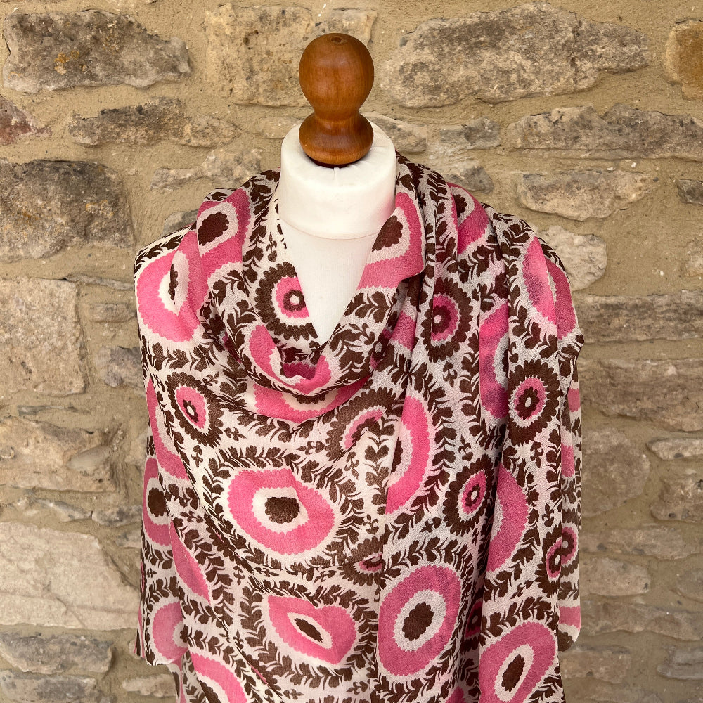 Patterned cashmere scarf on a mannequin against a stone wall background
