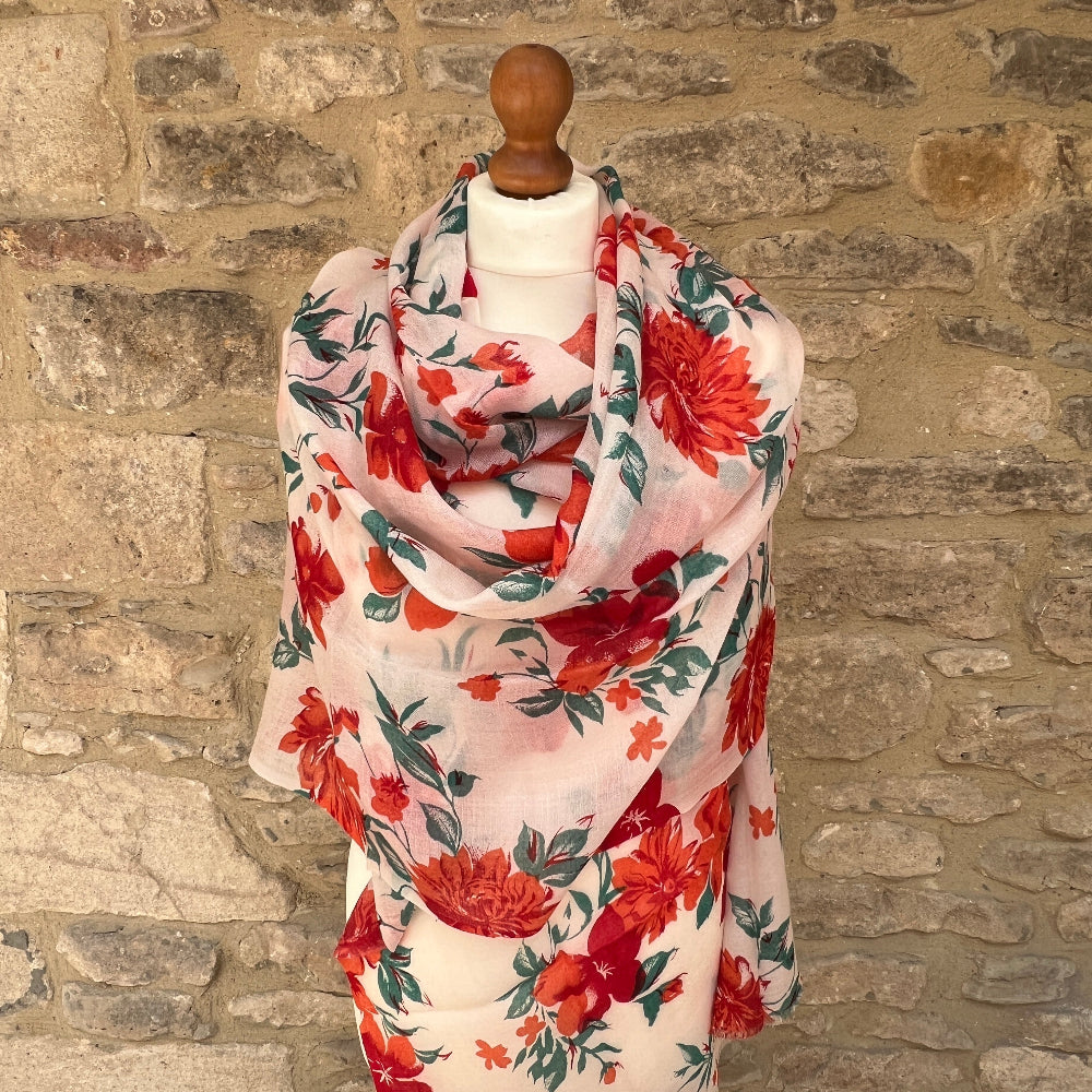 Cashmere printed Floral scarf with red flowers draped over a mannequin against a stone wall.