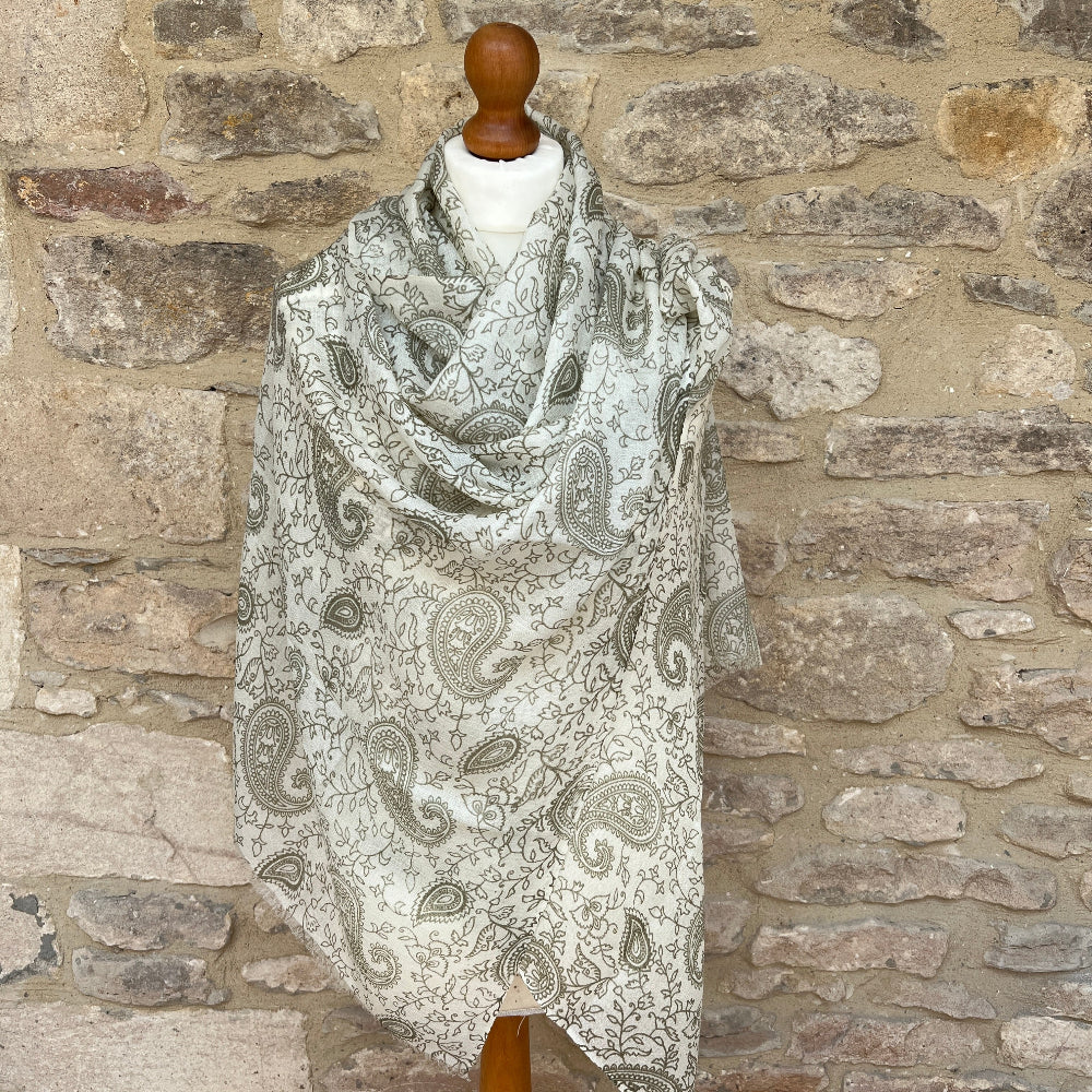 Paisley patterned scarf draped over a mannequin against a stone wall background