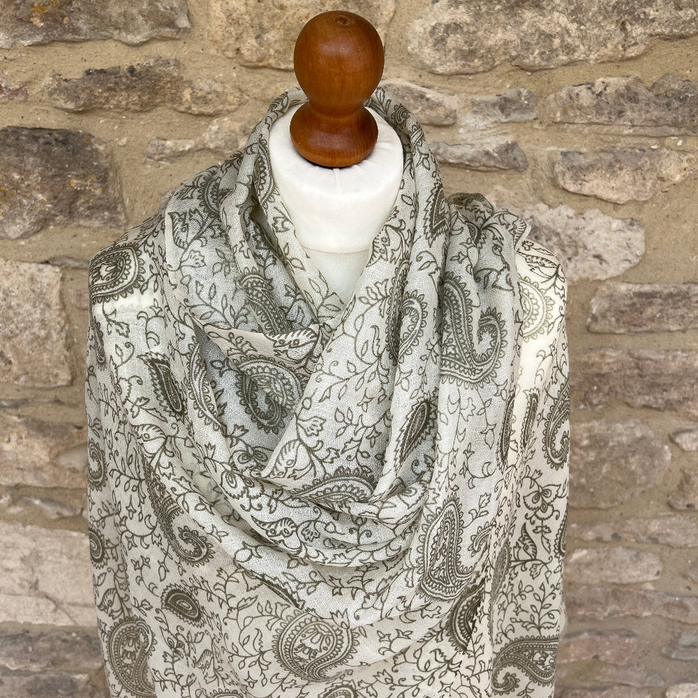 Paisley patterned scarf draped over a mannequin against a stone wall background