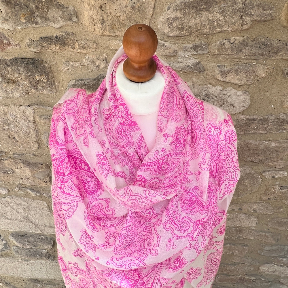 Pink paisley scarf on a mannequin against a stone wall background