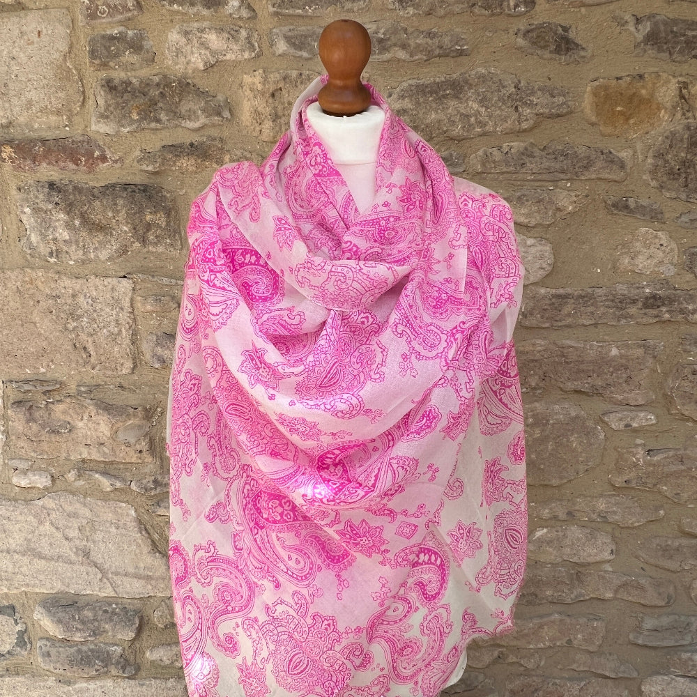 Pink paisley scarf on a mannequin against a stone wall background