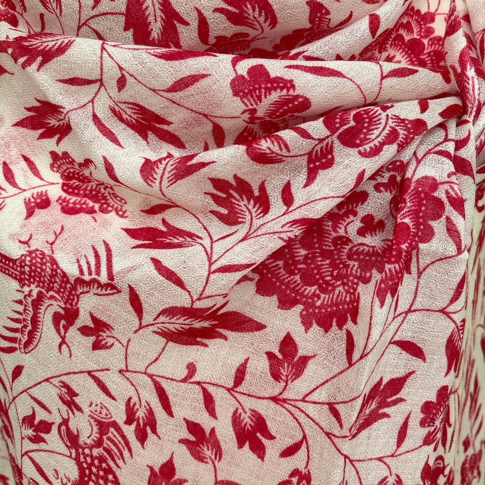 Pink floral patterned cashmere scarf on a mannequin against a stone wall background