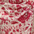 Pink floral patterned cashmere scarf on a mannequin against a stone wall background