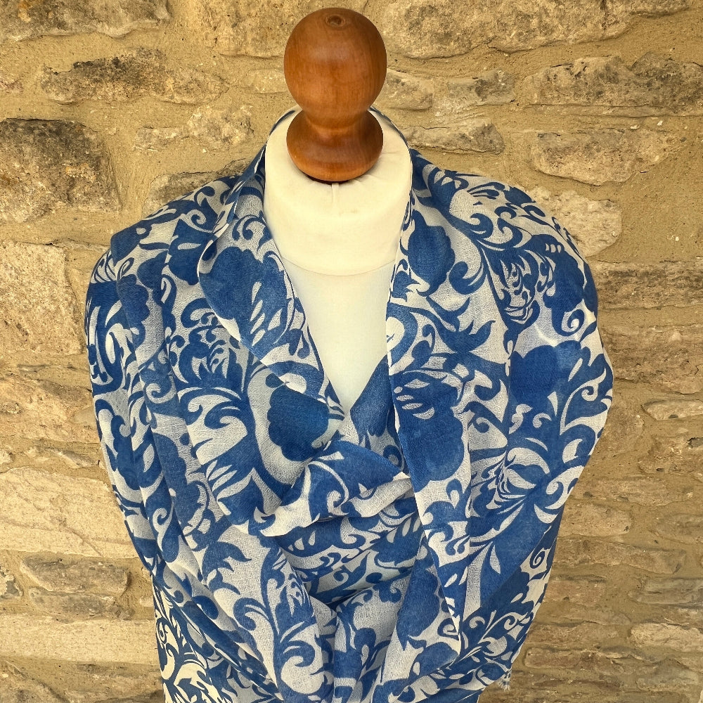 Blue and white patterned cashmere scarf / pashmina on a mannequin against a stone wall background