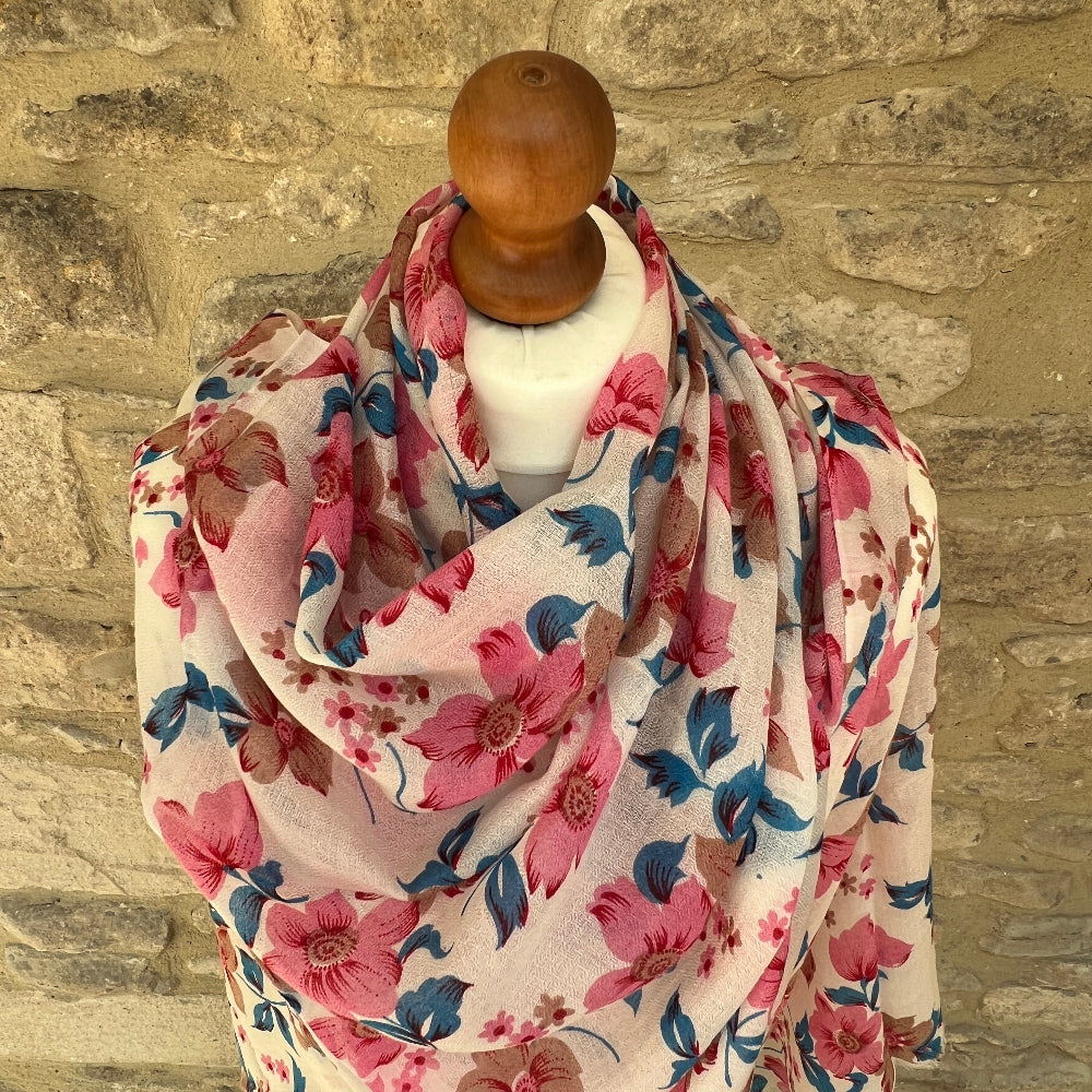 Floral patterned cashmere scarf on a mannequin against a stone wall background