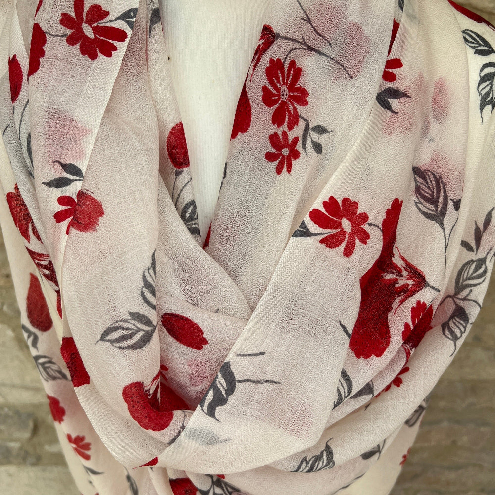 Cashmere floral patterned scarf pashmina with red flowers on a white background against a stone wall background.