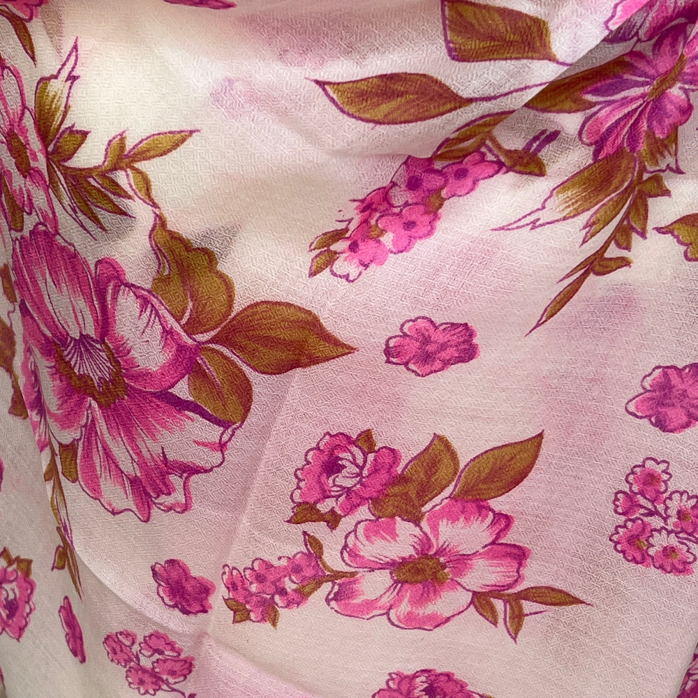 Cashmere pink floral pashmina scarf on a mannequin against a stone wall background.