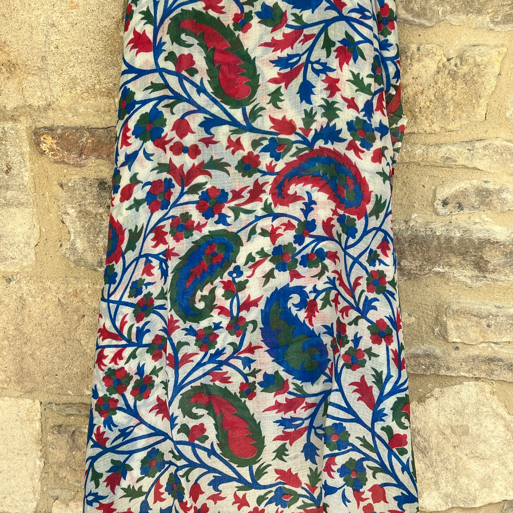Close-up of a gossamer light, cashmere pashmina scarf with intricate floral pattern in red, blue, and green on a white background.