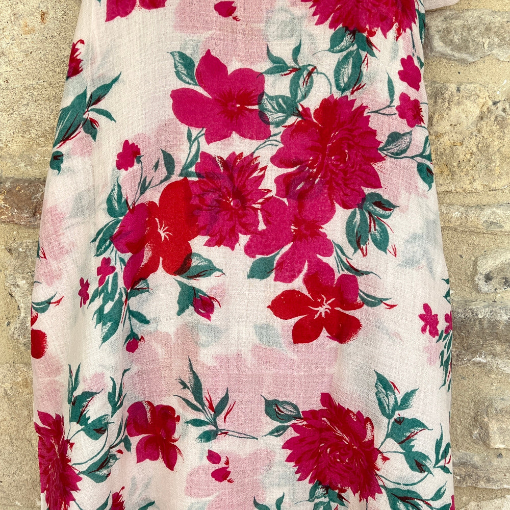 A Floral patterned cashmere pashmina scarf with red and pink flowers on a textured stone background