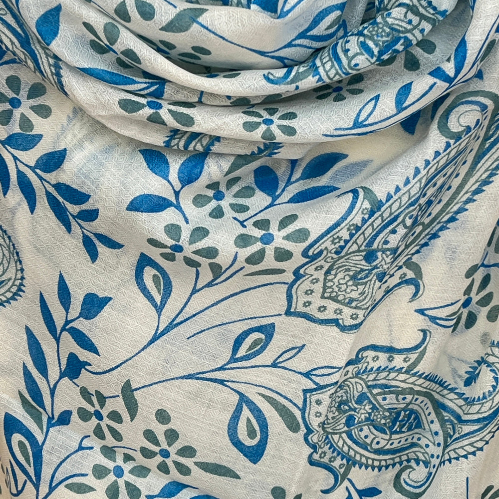 Close-up of a cashmere scarf with blue and green floral and paisley patterns on a white background
