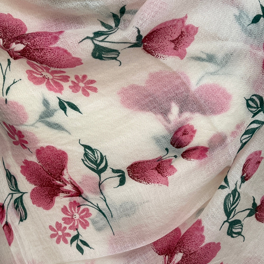 Delicate pink floral cashmere scarf on a mannequin against a stone wall background