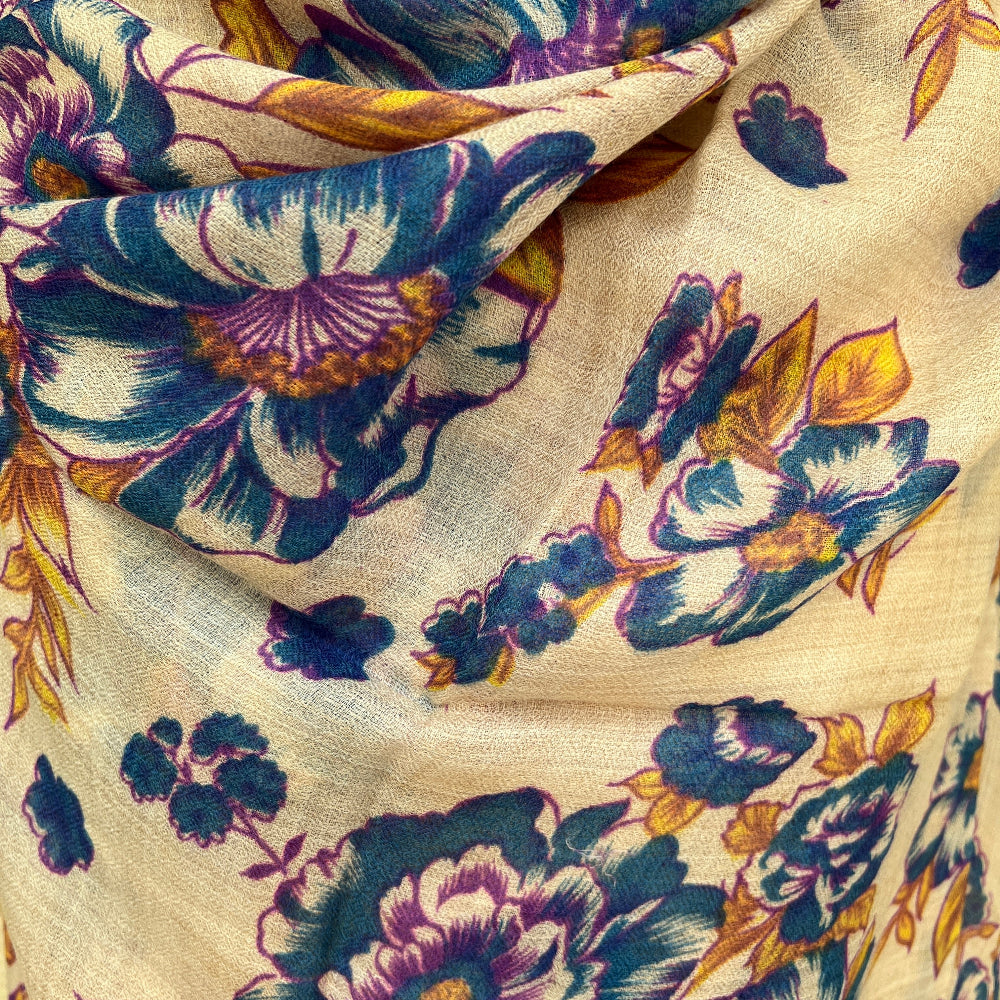 Close-up of a mfloral cashmere pashmina with blue, purple, and yellow colors on a beige background.