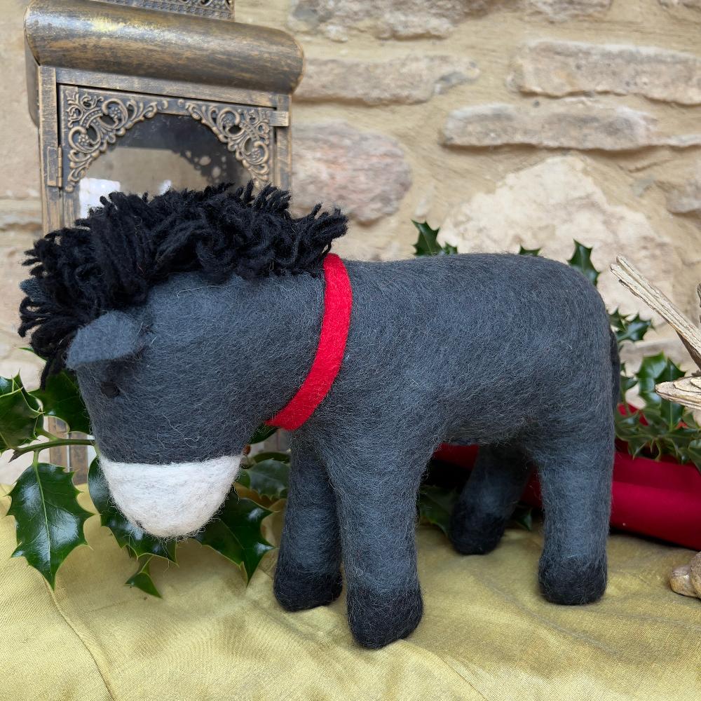Discover the charm of our artisan, handcrafted felted wool larger sized Donkey.&amp;nbsp;

A delightful festive companion perfect for adding warmth to your seasonal décor. Each piece is handcrafted crafted from pure felted wool with hand-stitched details and dressed in a vibrant red scarf that captures the spirit of the season. Shown on gold silk fabric, against a cotswold stone wall with festive holly, candles and decorative accents. 