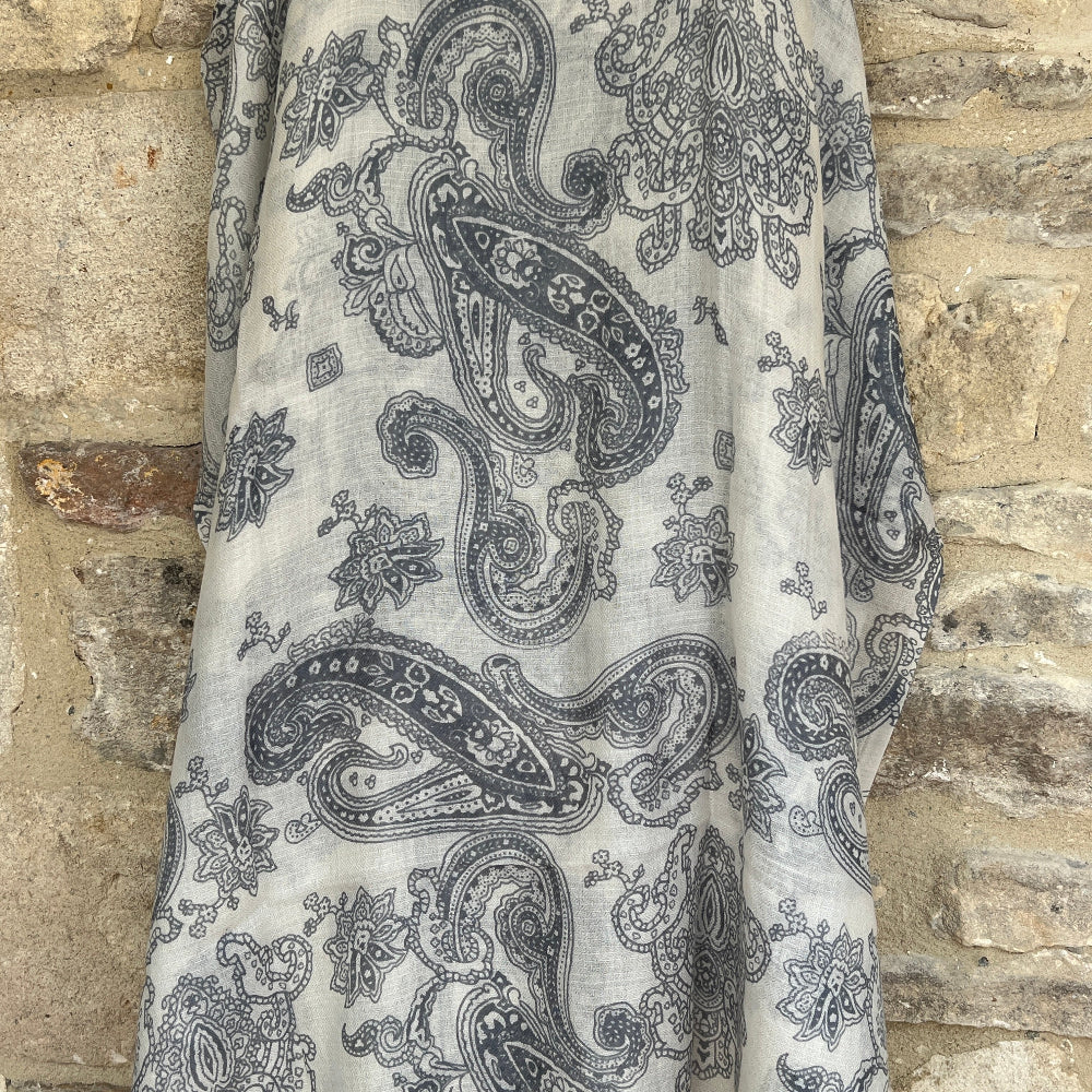 Grey Paisley patterned cashmere pashmina draped over a stone wall
