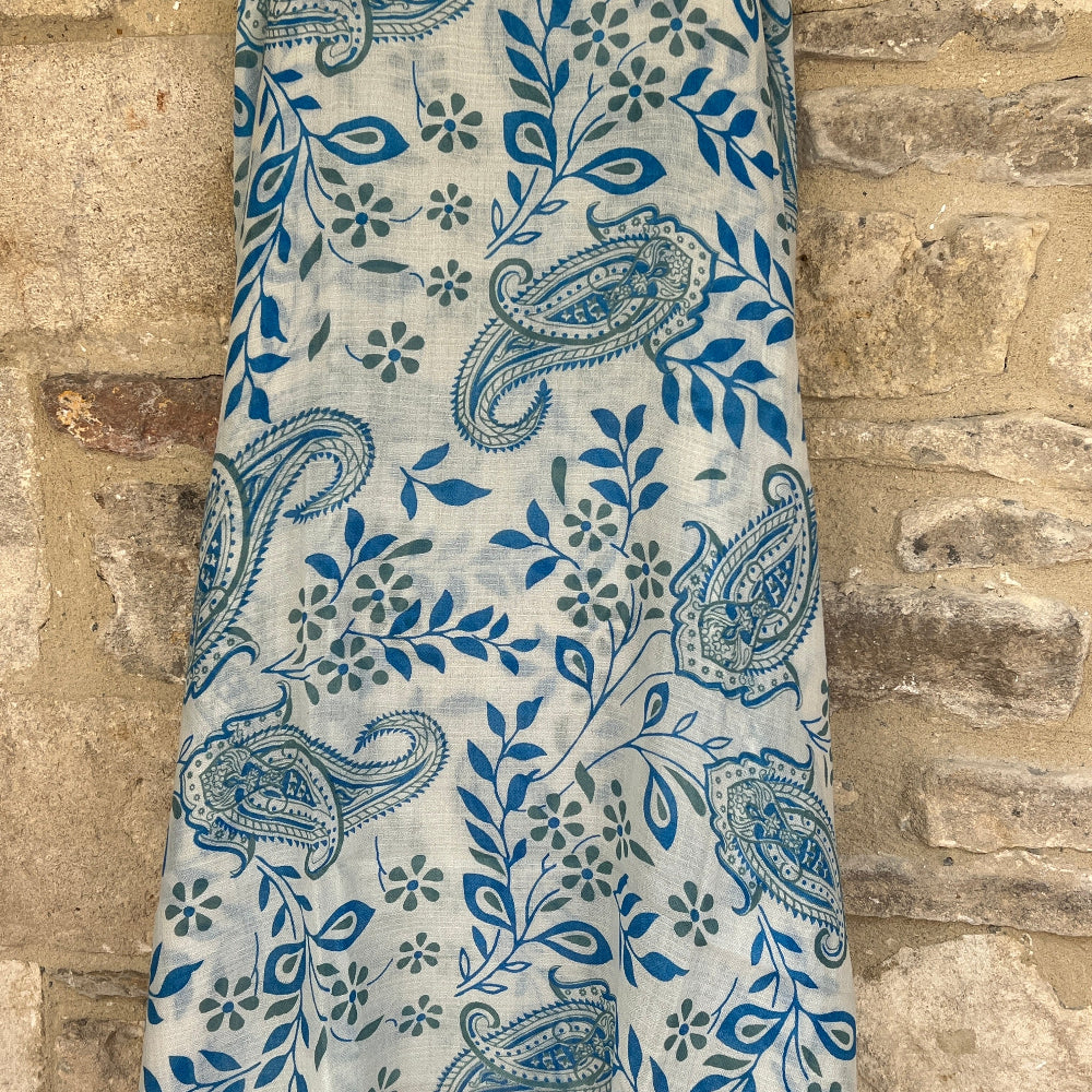 Blue paisley patterned cashmere pashmina scarf against a stone wall background