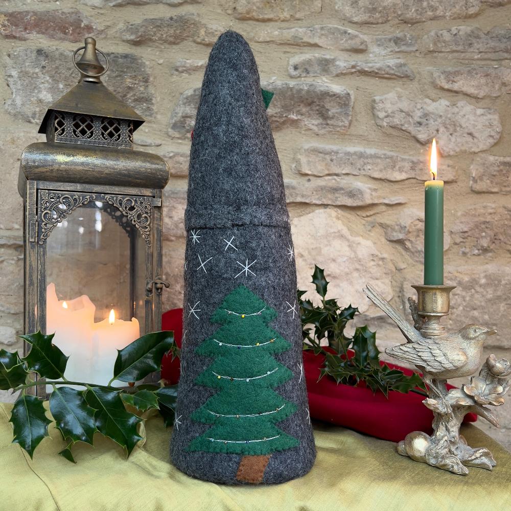 Bring festive charm to your home with this exquisite artisan handcrafted Father Christmas figure.

Meticulously created from premium felted wool, it showcases a luxuriously soft faux fur beard and intricate hand-stitched snowflake embellishments adorning the hat and body. The design features charming holly and berry appliqués on the hat, while the back displays an ornate Christmas tree decorated with sparkling beads. Shown with festive holly, candles and decorative items against a stone wall background. 