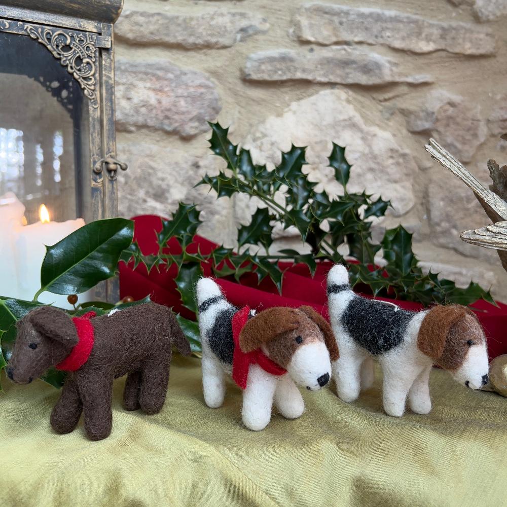 This charming felted wool &#39;Patch Dog&#39; showcases artisanal craftsmanship at its finest.

Meticulously hand-stitched from premium wool, each piece features a distinctive patchwork design with warm brown tones adorning the head and ears. A thoughtfully curated decorative accent or gift for pet lovers who appreciate handmade quality.  Shown with holly, red and gold fabric against a stone wall background.