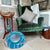 Pet Cave next to a Green velvet armchair with a patterned pillow in a room with a wooden side table and decorative items.
