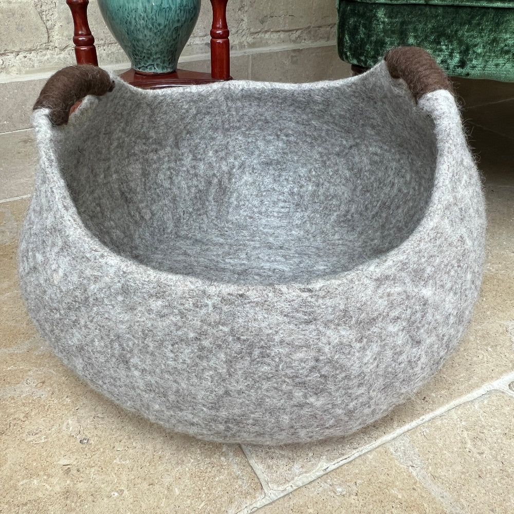 Pure Wool Felted Milk Chocolate Brown with Brown Handled storage basket on a tiled floor next to a green armchair with decorative items