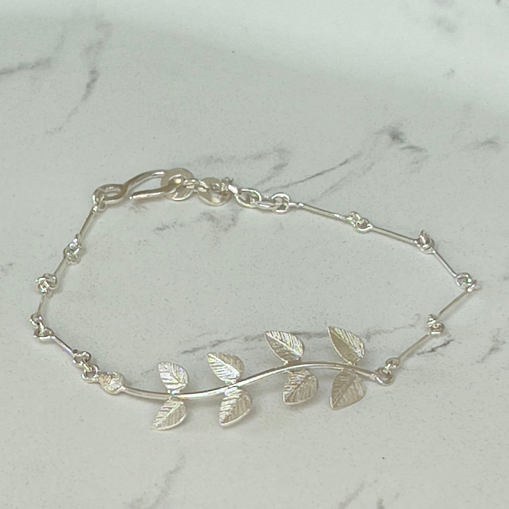 Handcrafted Silver 'Leaf' Bracelet by Lily's Leaves shown on a grey and white marble surface