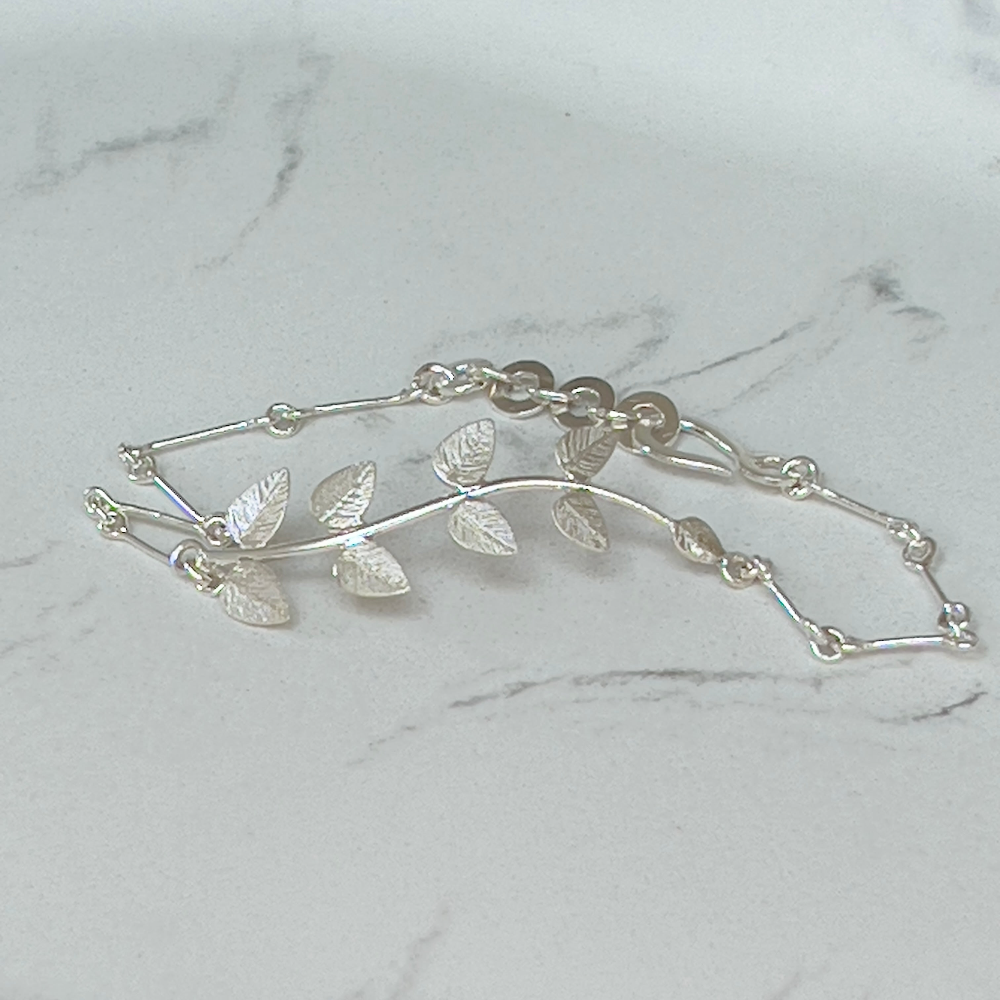 Handcrafted Silver 'Leaf' Bracelet by Lily's Leaves shown on a grey and white marble surface