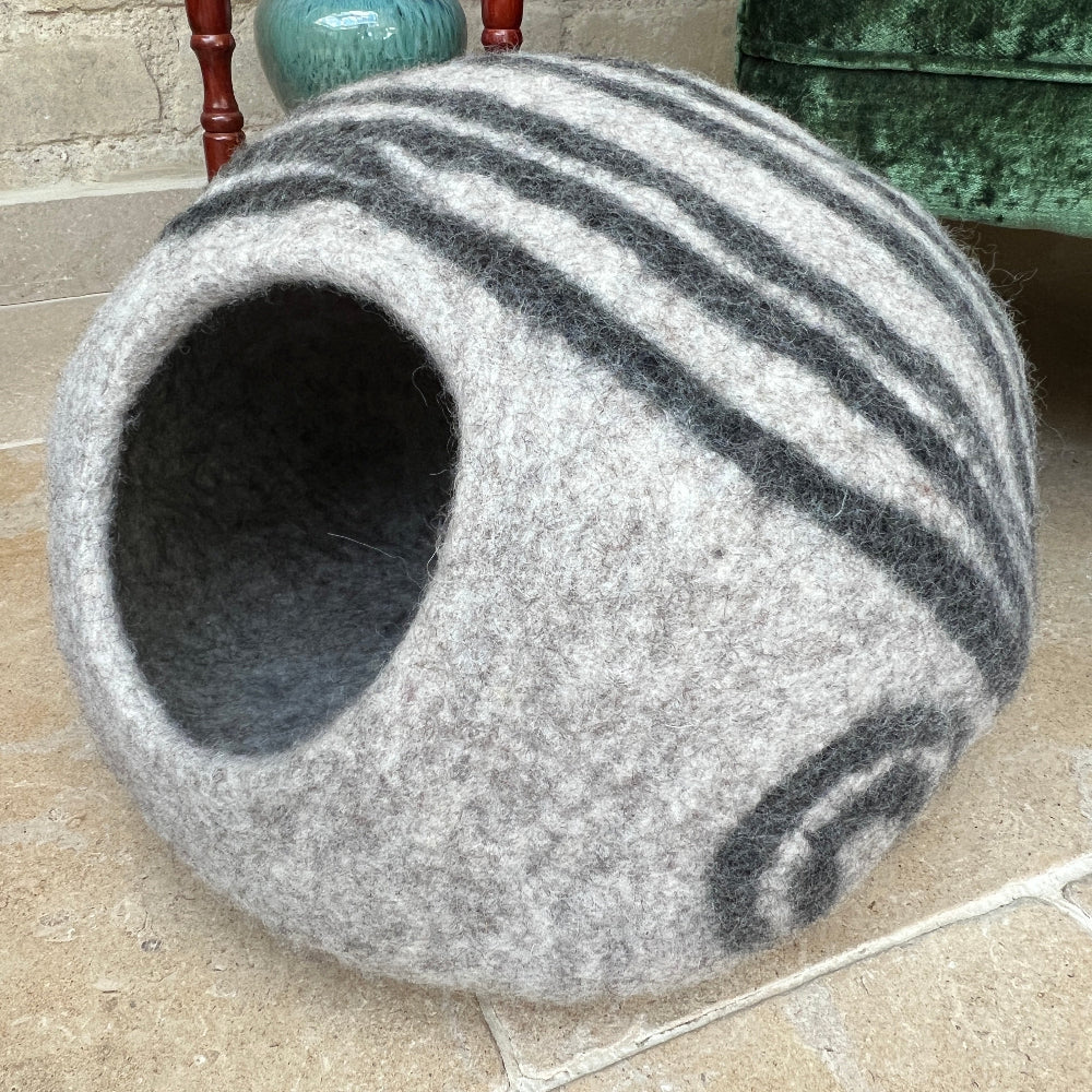 Give your pet the luxury they deserve with this handcrafted felted wool cave. Made from 100% New Zealand wool and naturally dyed, it delivers unmatched softness and breathability that keeps your companion cosy year-round. This sanctuary maintains superior air circulation for optimal comfort. At approx. 45cm wide and 30cm tall, it's the perfect size for nesting, yet folds away effortlessly when you need extra space. Beyond being a cherished pet retreat. Shown on a stone floor against a green velvet chair.