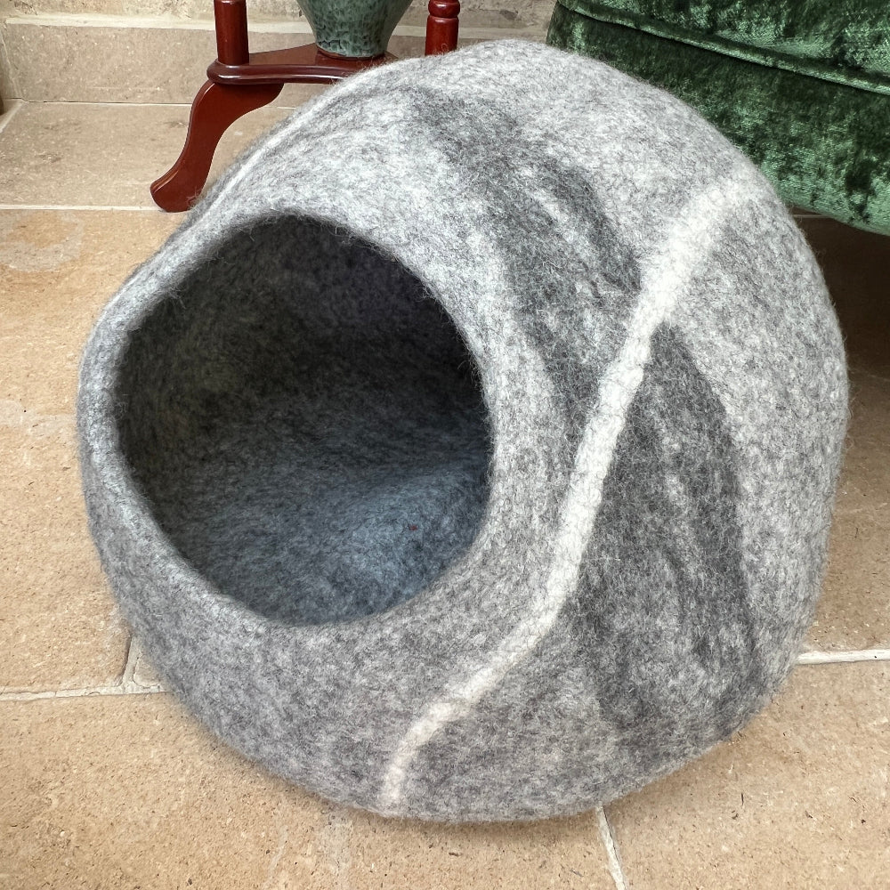 Crafted from New Zealand felted wool and coloured with natural dyes, this elegant pet cave offers your companion a sanctuary of warmth and comfort.

The breathable, chemical-free construction maintains air circulation, while the sophisticated grey finish complements any interior.

This versatile piece serves equally well as a pet bed, mat, or decorative storage.

Handmade by a dedicated family business prioritising fair wages and environmental responsibility.  Shown against a green armchair on a stone floor