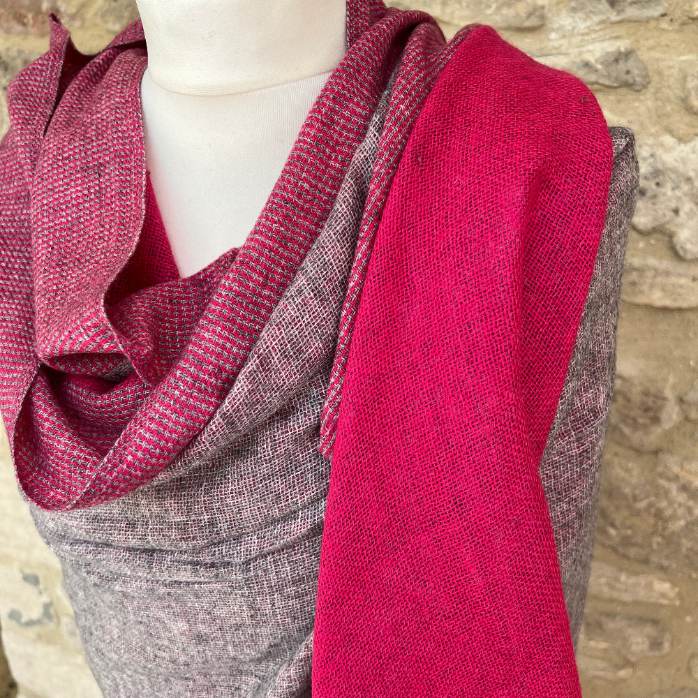Handwoven Cashmere Reversible Pashmina - Pink &amp; Grey.  Mannequin  wearing a pink and gray cashmere scarf against a cotswold stone wall background