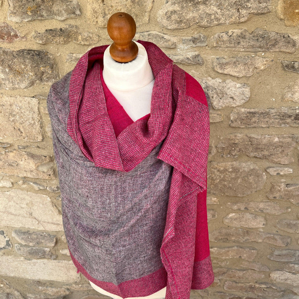 Handwoven Cashmere Reversible Pashmina - Pink & Grey.  Mannequin  wearing a pink and gray cashmere scarf against a cotswold stone wall background