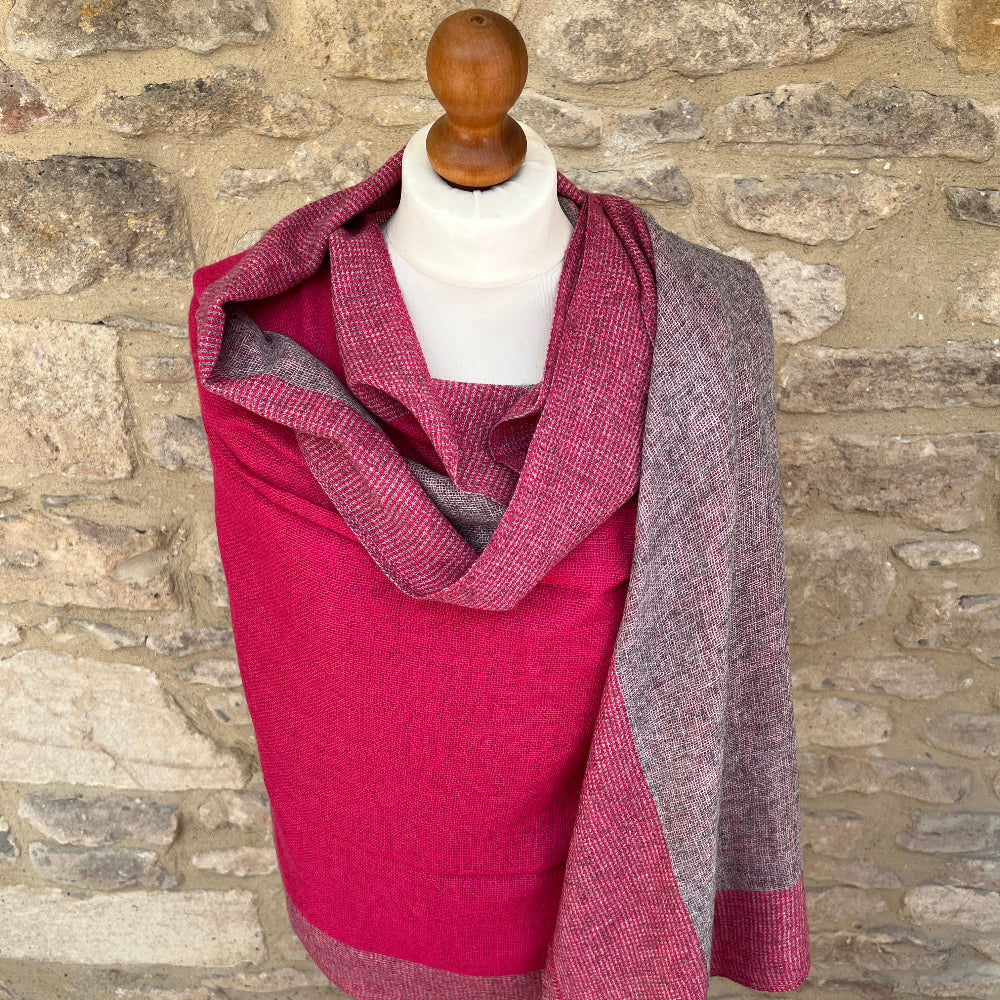Handwoven Cashmere Reversible Pashmina - Pink &amp; Grey.  Mannequin  wearing a pink and gray cashmere scarf against a cotswold stone wall background