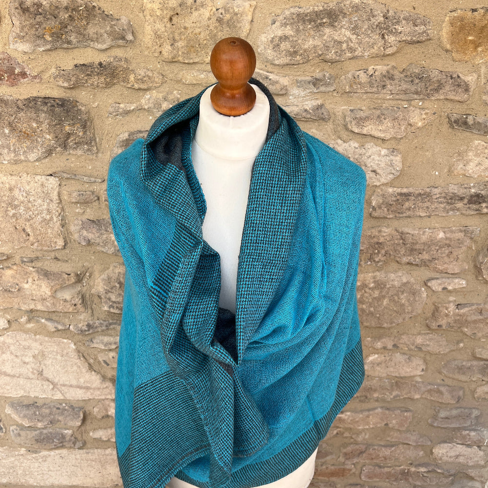 Handwoven Cashmere Reversible Pashmina - Teal &amp; Grey
Teal woven cashmere shawl draped over a mannequin against a  cotswold stone wall background