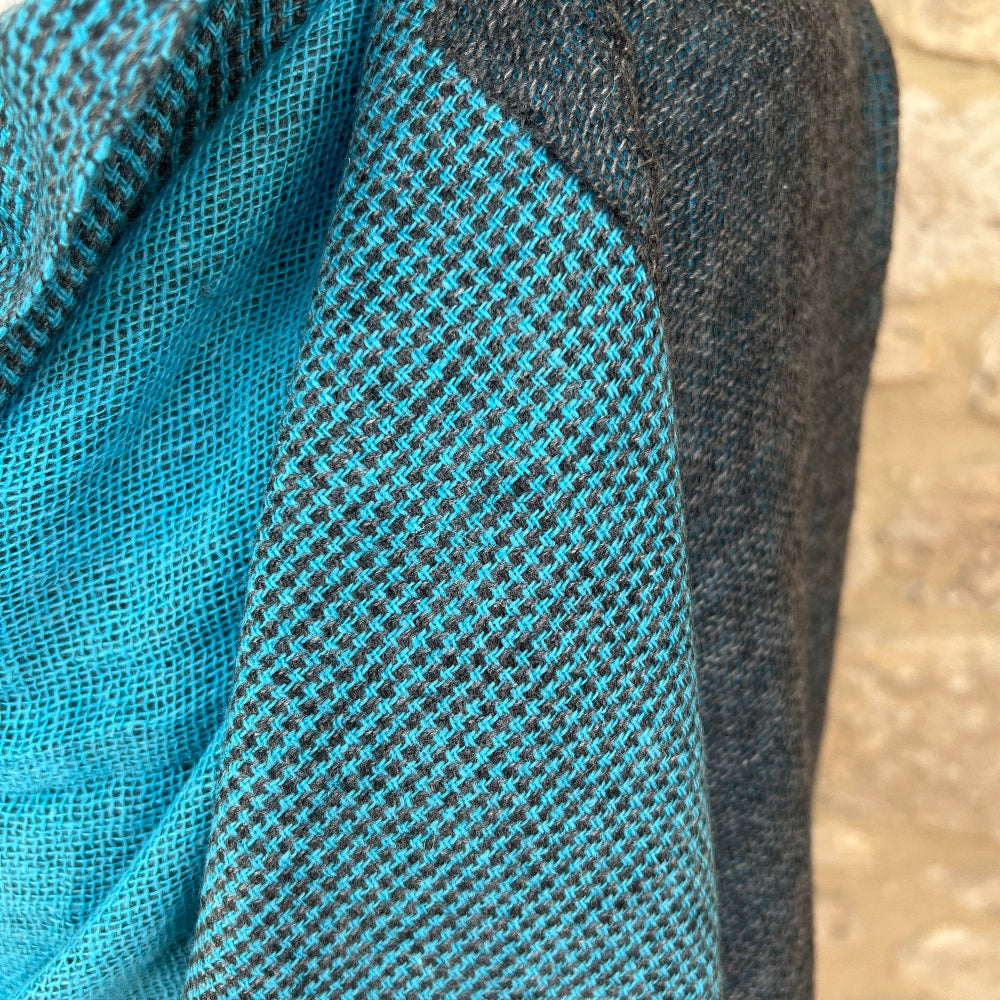 Close up. Handwoven Cashmere Reversible Pashmina - Teal &amp; Grey
Teal woven cashmere shawl draped over a mannequin against a  cotswold stone wall background