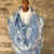 Mannequin wearing a blue and white paisley patterned cashmere pashmina scarf against a stone wall.
