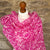 Mannequin wearing a pink floral scarf against a stone wall background