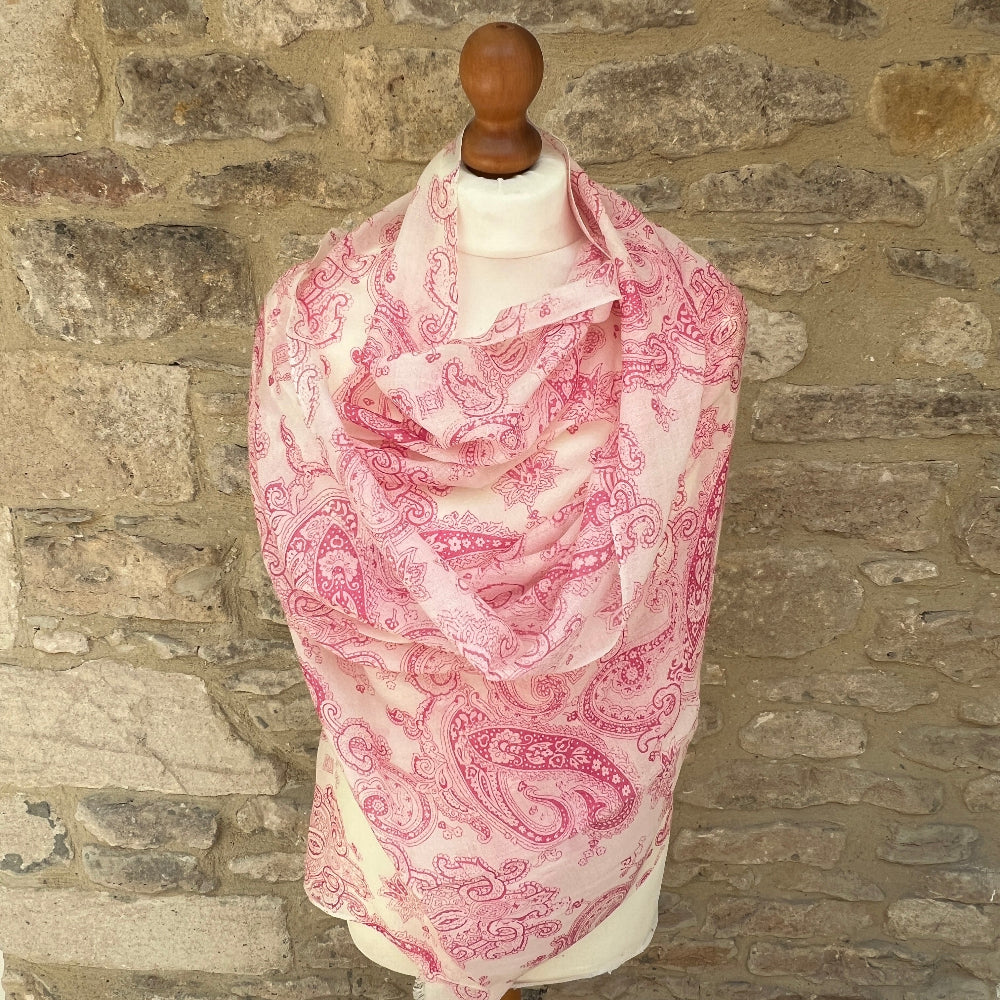 Pink paisley cashmere scarf on a mannequin against a stone wall background